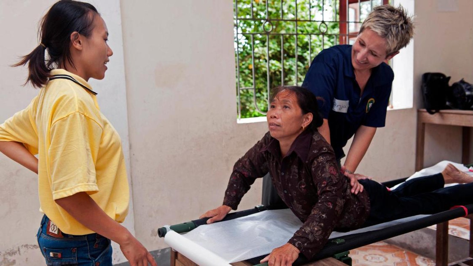 A physiotherapist treats a woman with back pain on a treatment table